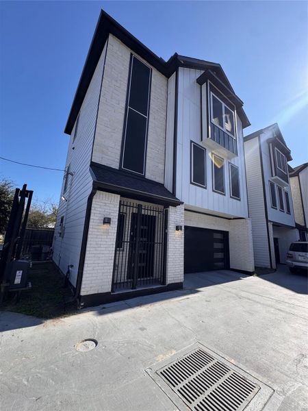 Contemporary three-story home featuring sleek black accents, large windows, and a secure gated entry, complete with an attached garage for convenience. Contemporary three-story home featuring sleek black accents, large windows, and a secure gated entry, complete with an attached garage for convenience.