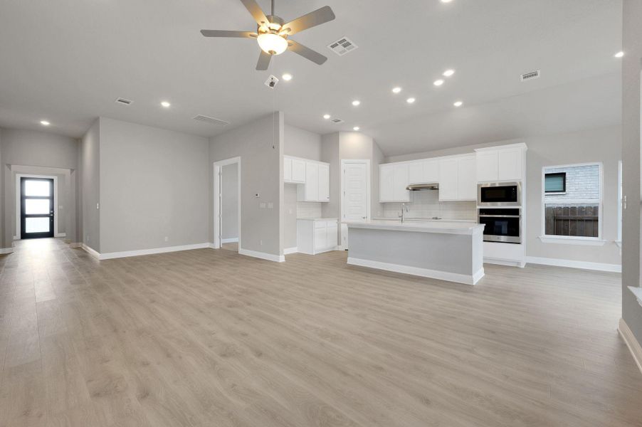 Unfurnished living room with light wood-style flooring, a ceiling fan, recessed lighting, and lofted ceiling