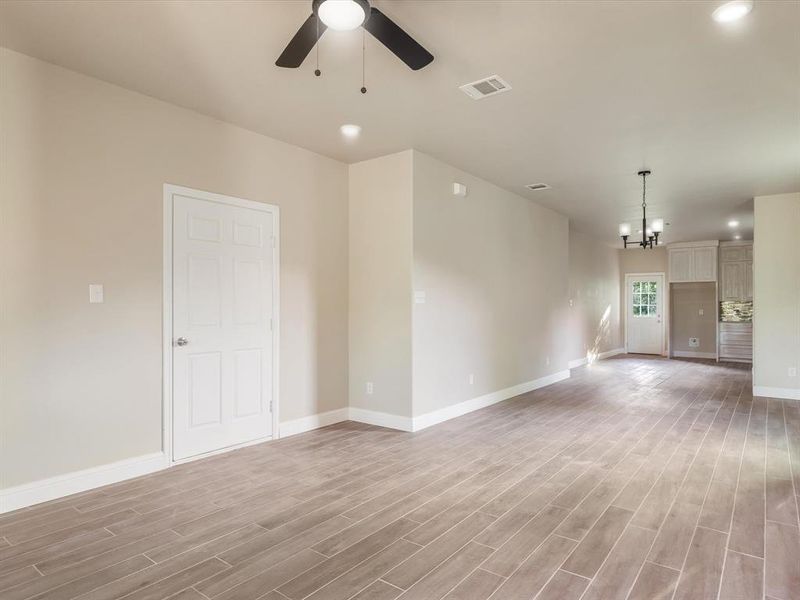Empty room featuring light wood-type flooring, a ceiling fan, a chandelier, and recessed lighting Empty room featuring light wood-type flooring, a ceiling fan, a chandelier, and recessed lighting