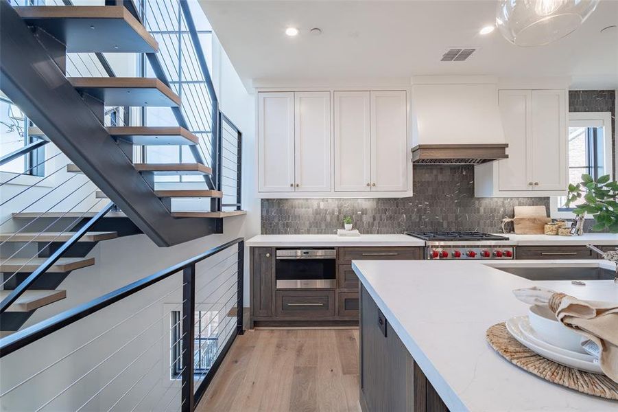 Kitchen with premium range hood, Wolf and Sub zero appliances, and light hardwood floors