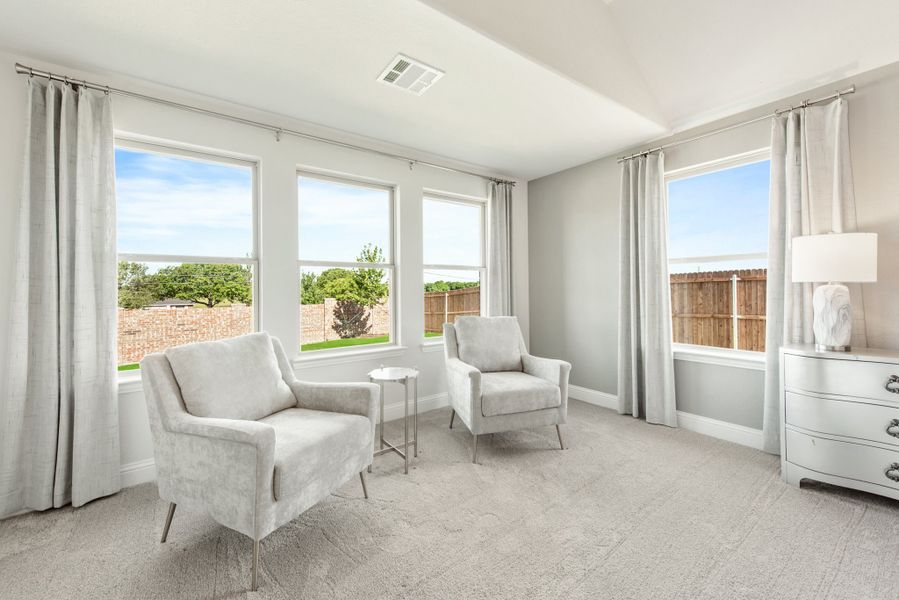 Sitting room with two gray accent chairs, carpet flooring, and large windows with backyard views