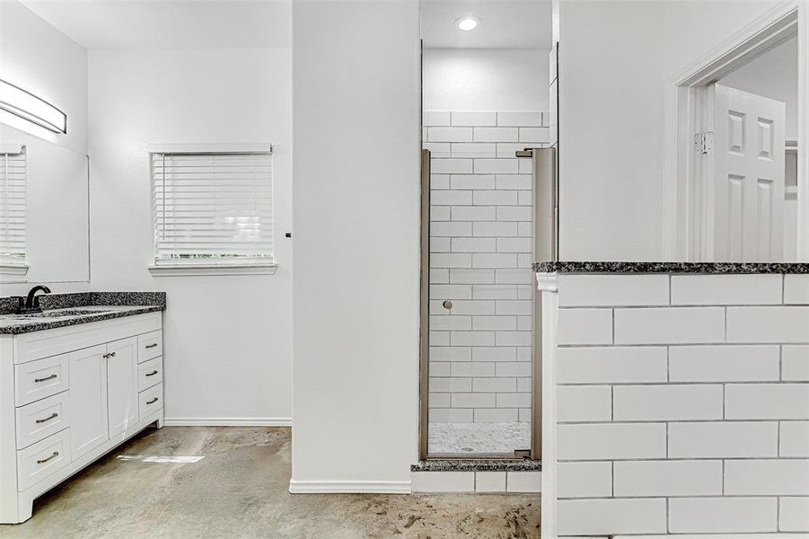 Bathroom with vanity, tiled shower, and concrete floors