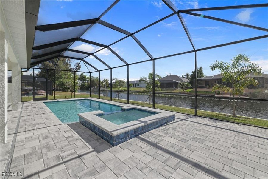 View of pool with a water view, glass enclosure, a sunroom, a pool with connected hot tub, and a patio​​‌​​​​‌​​‌‌​​‌​​​‌‌​​‌‌​‌​​​‌​‌​‌​​​​‌‌ area
