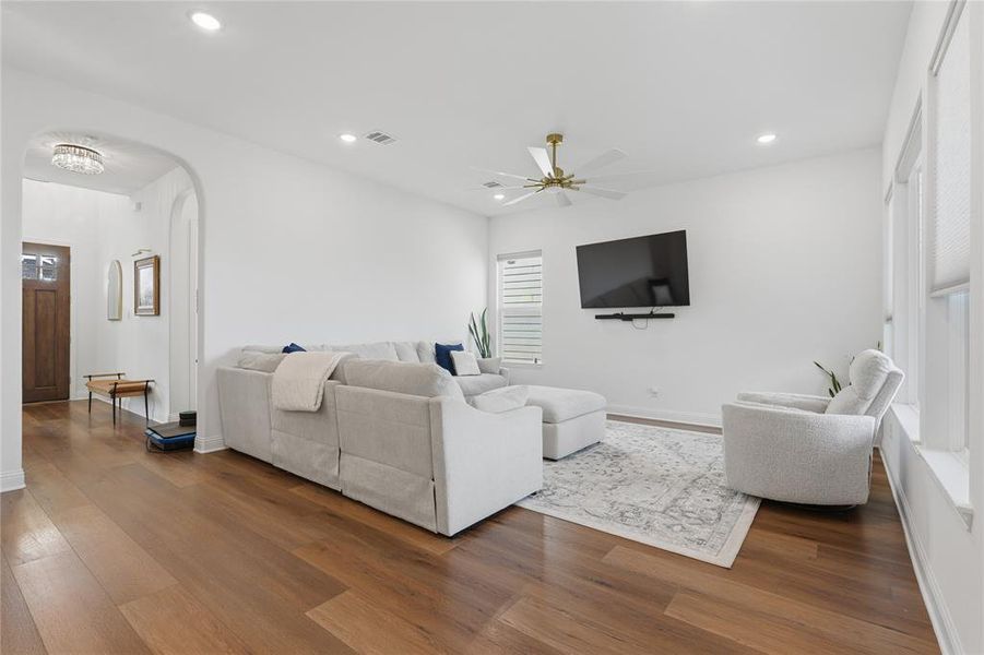 Spacious living area featuring wood-finish flooring, recessed lighting, and a modern ceiling fan with brass accents Spacious living area featuring wood-finish flooring, recessed lighting, and a modern ceiling fan with brass accents