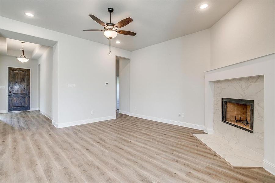 Unfurnished living room with light hardwood / wood-style flooring, ceiling fan, and a premium fireplace