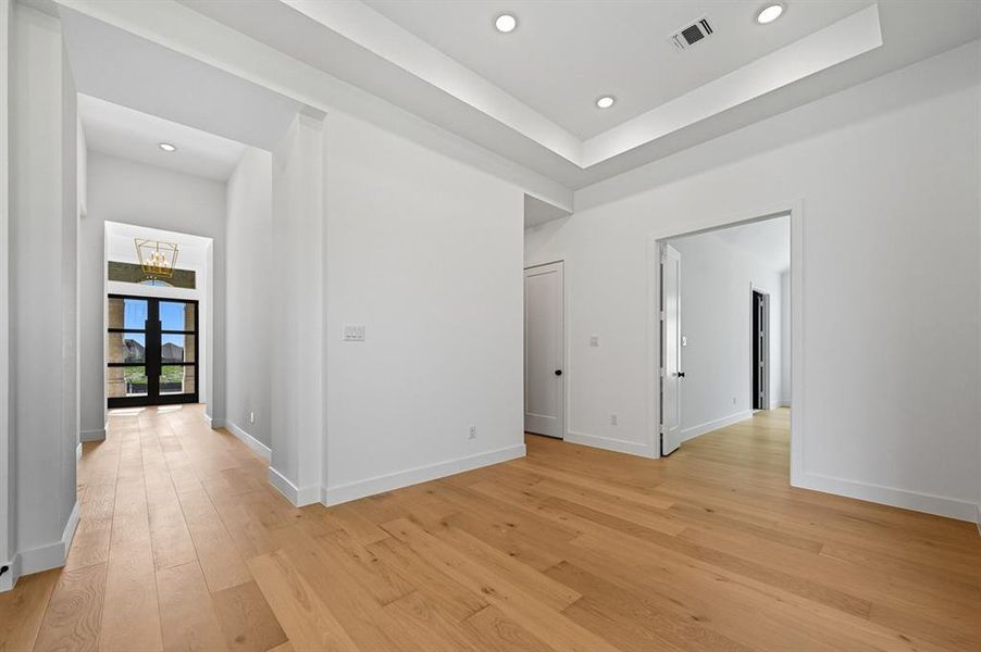 Spare room featuring a raised ceiling, light wood-style floors, and recessed lighting Spare room featuring a raised ceiling, light wood-style floors, and recessed lighting