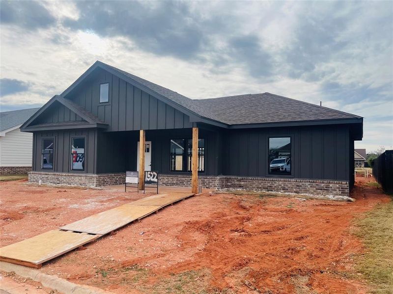 View of front of house featuring board and batten siding, a shingled roof, brick siding, and covered porch View of front of house featuring board and batten siding, a shingled roof, brick siding, and covered porch