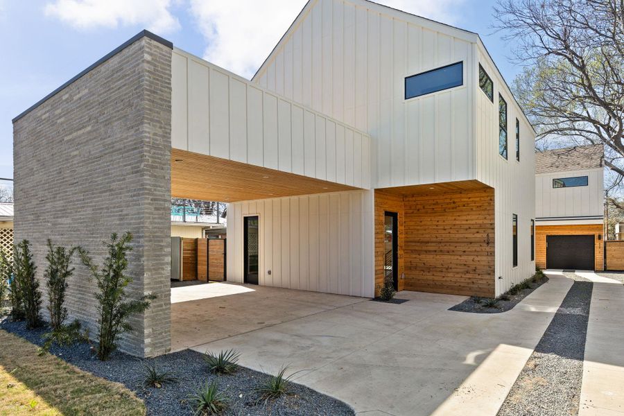 Rear view of house featuring an attached carport, board and batten siding, and driveway