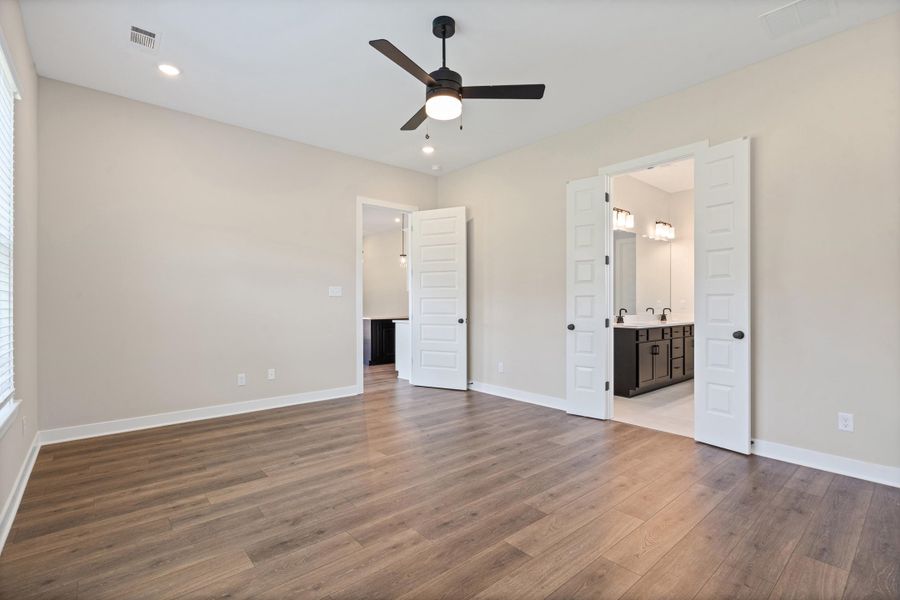Spacious room featuring wood-finish flooring, light neutral walls, and a contemporary ceiling fan with integrated lighting Spacious room featuring wood-finish flooring, light neutral walls, and a contemporary ceiling fan with integrated lighting