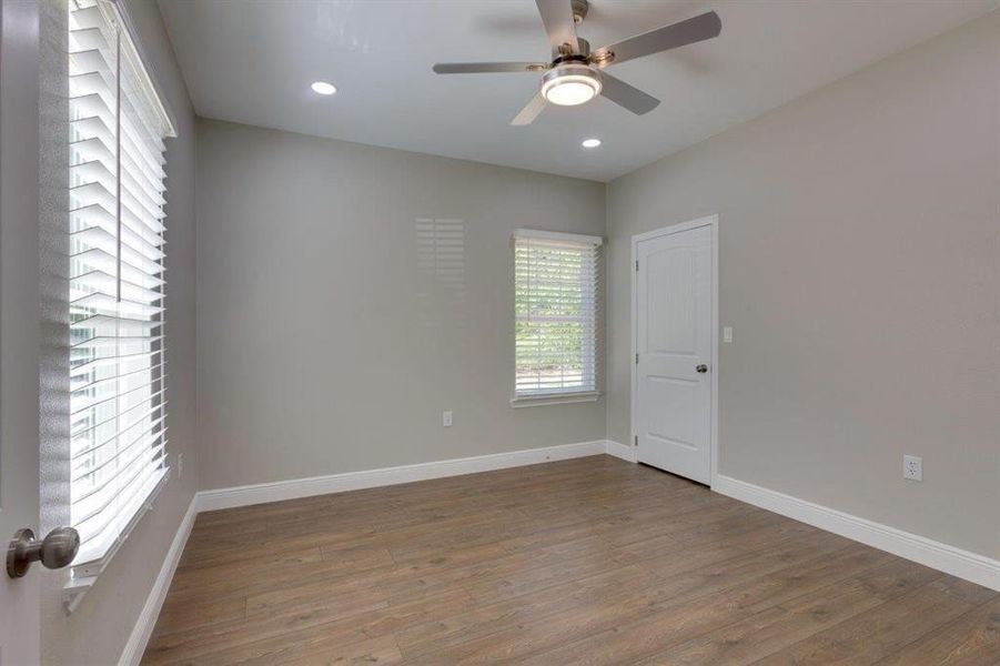 Unfurnished room with plenty of natural light, wood finished floors, recessed lighting, and a ceiling fan