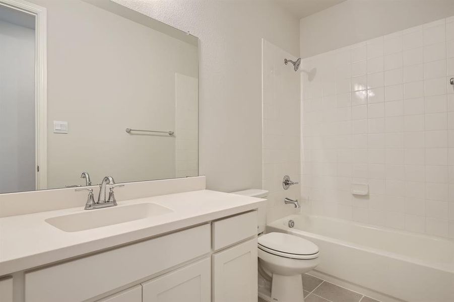 Full bathroom featuring tile patterned flooring, tiled shower / bath, vanity, and toilet