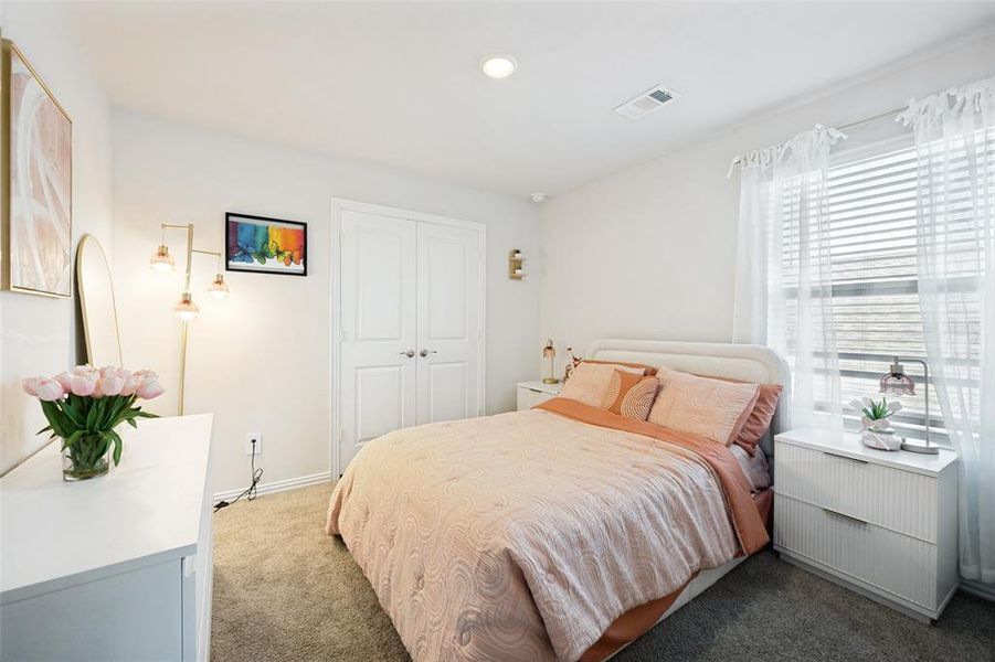 Carpeted bedroom featuring a double window with blinds, white walls, and a built-in double-door closet Carpeted bedroom featuring a double window with blinds, white walls, and a built-in double-door closet