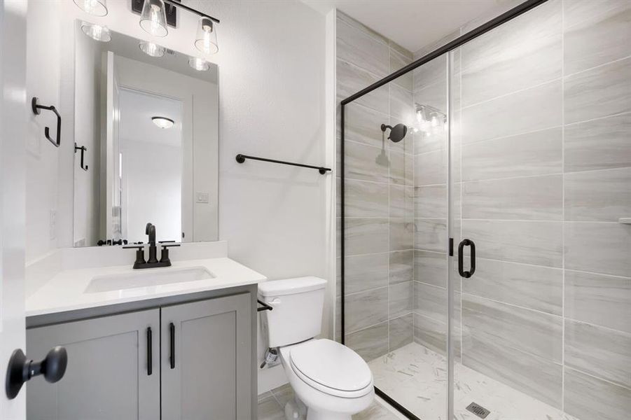 Bathroom featuring a glass-enclosed shower with tiled walls and a tiled floor