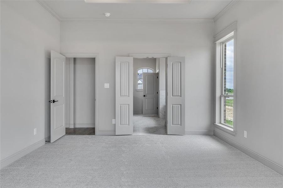 Unfurnished bedroom with ornamental molding and light colored carpet