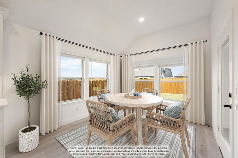 Bright dining nook with round table, wicker chairs, large windows, and white curtains overlooking a fenced backyard Bright dining nook with round table, wicker chairs, large windows, and white curtains overlooking a fenced backyard