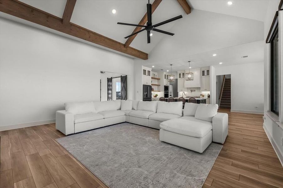 Living room featuring beamed ceiling, ceiling fan, and high vaulted ceiling