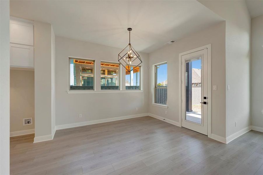 Unfurnished dining area with hanging lights, plenty of natural light, and light wood-type flooring