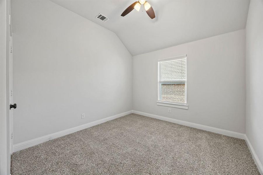 Empty room with carpet flooring, vaulted ceiling, and ceiling fan