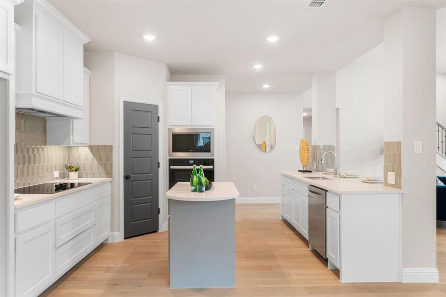 Kitchen with white cabinets, backsplash, black appliances, and light wood-type flooring