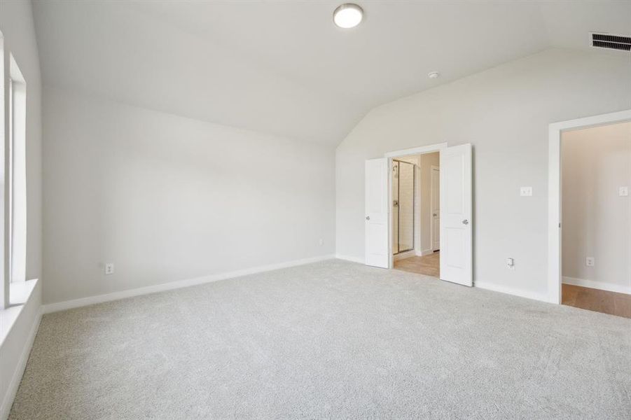 Another view of the primary bedroom showing the ensuite bathroom and the door