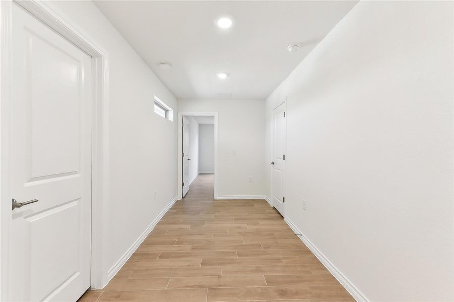 Hallway with recessed lighting, light wood-style flooring, and baseboards Hallway with recessed lighting, light wood-style flooring, and baseboards