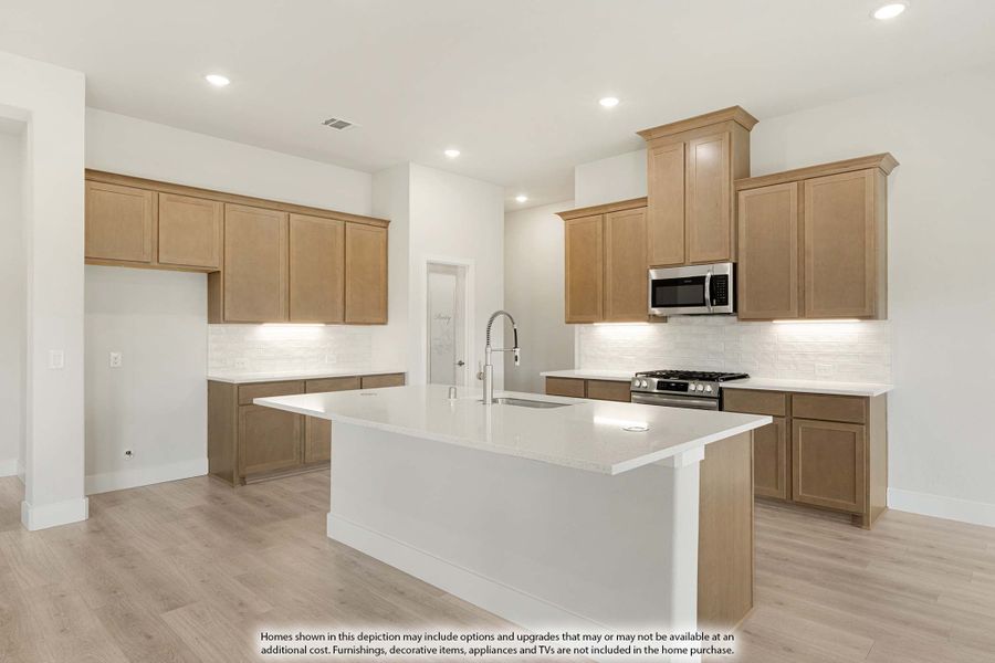 Kitchen with center island, light wood cabinets, white countertops, and stainless steel appliances on light hardwood floors. Kitchen with center island, light wood cabinets, white countertops, and stainless steel appliances on light hardwood floors.