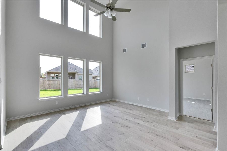Unfurnished living room featuring a high ceiling, ceiling fan, and light wood-style floors Unfurnished living room featuring a high ceiling, ceiling fan, and light wood-style floors