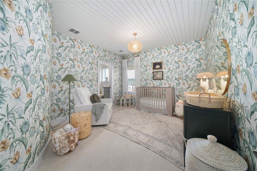 Carpeted bedroom with a crib and wood ceiling