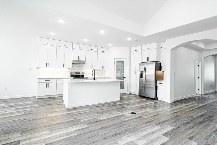 A streamlined kitchen layout boasts pristine white cabinetry, contemporary appliances, and an inviting island centerpiece. A streamlined kitchen layout boasts pristine white cabinetry, contemporary appliances, and an inviting island centerpiece.