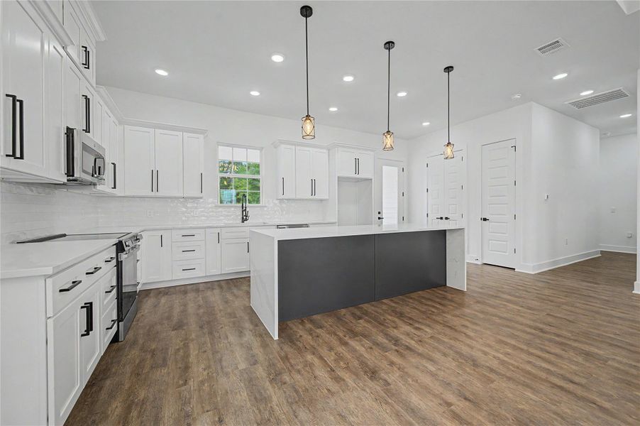 Open living and dining area with vaulted ceiling, statement chandelier, and warm wood-look flooring.