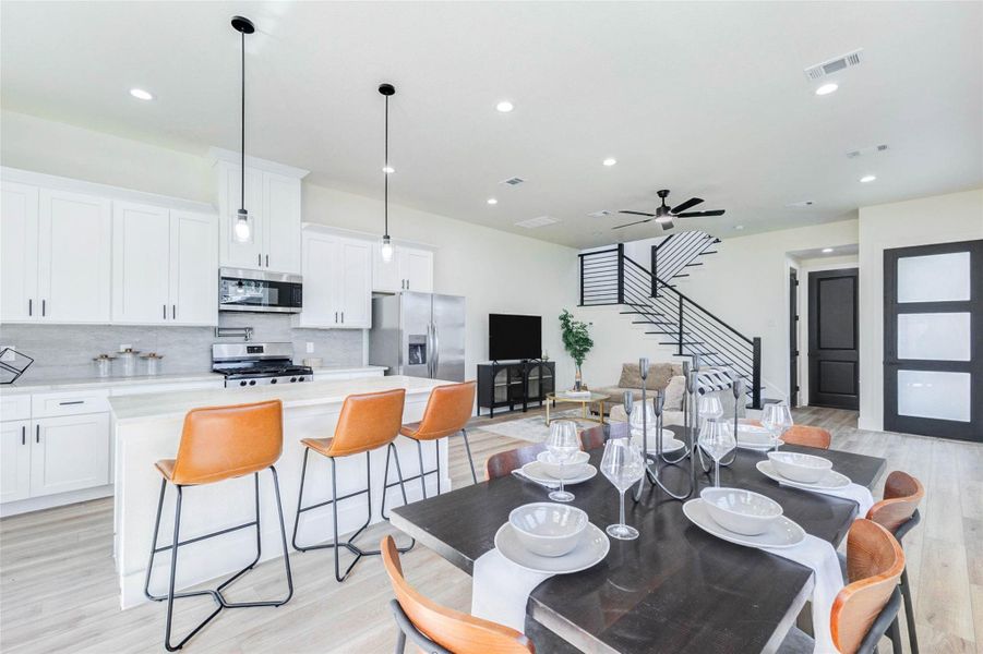 A chef-inspired kitchen boasts white Shaker-style cabinetry, light stone countertops, and a full suite of stainless steel appliances.