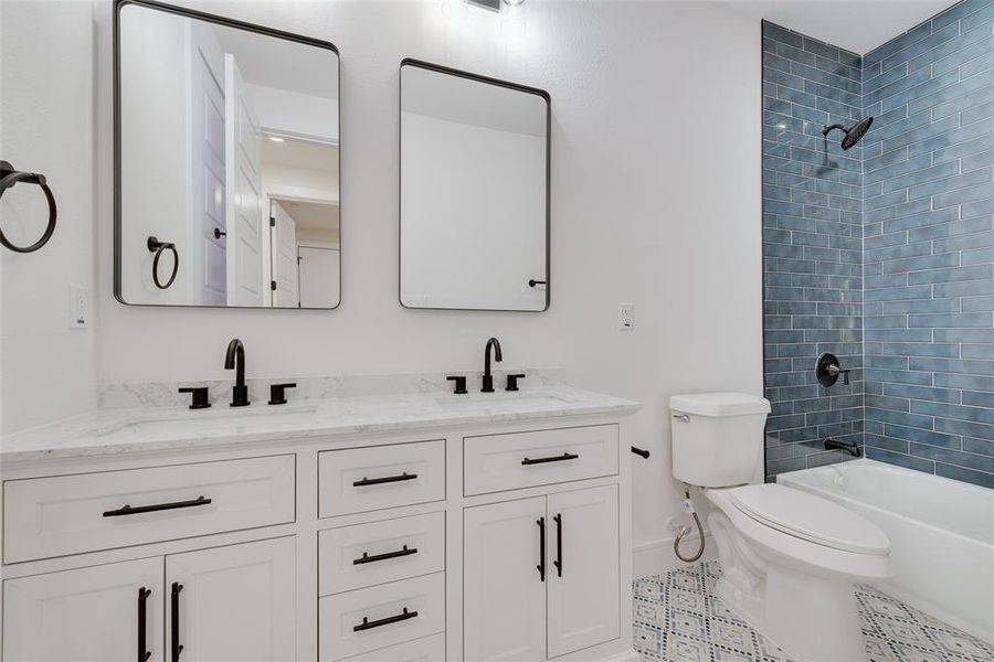 Full bathroom featuring vanity, tiled shower / bath combo, tile patterned floors, and toilet