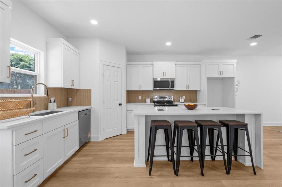 Kitchen featuring stainless steel appliances, backsplash, white cabinets, and recessed lighting Kitchen featuring stainless steel appliances, backsplash, white cabinets, and recessed lighting