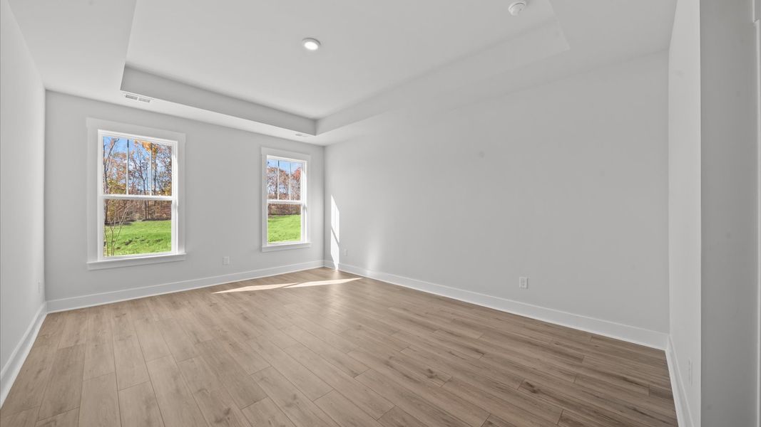 Serene and stylish primary bedroom featuring hardwood flooring and a thoughtful, modern layout