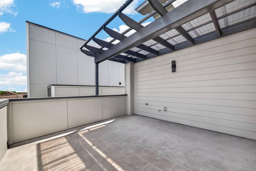 This image shows a modern, spacious rooftop terrace with a pergola. It features a sleek, minimalist design with light-colored tiles and walls, offering ample outdoor space with partial shade. Ideal for relaxation or entertaining. This image shows a modern, spacious rooftop terrace with a pergola. It features a sleek, minimalist design with light-colored tiles and walls, offering ample outdoor space with partial shade. Ideal for relaxation or entertaining.