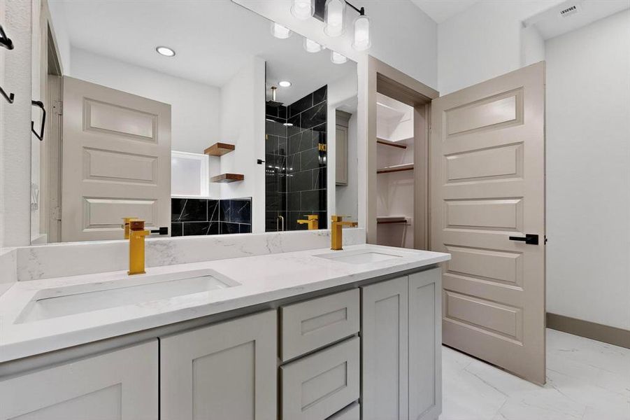 Bathroom with a stall shower, double vanity, and light marble finish floors
