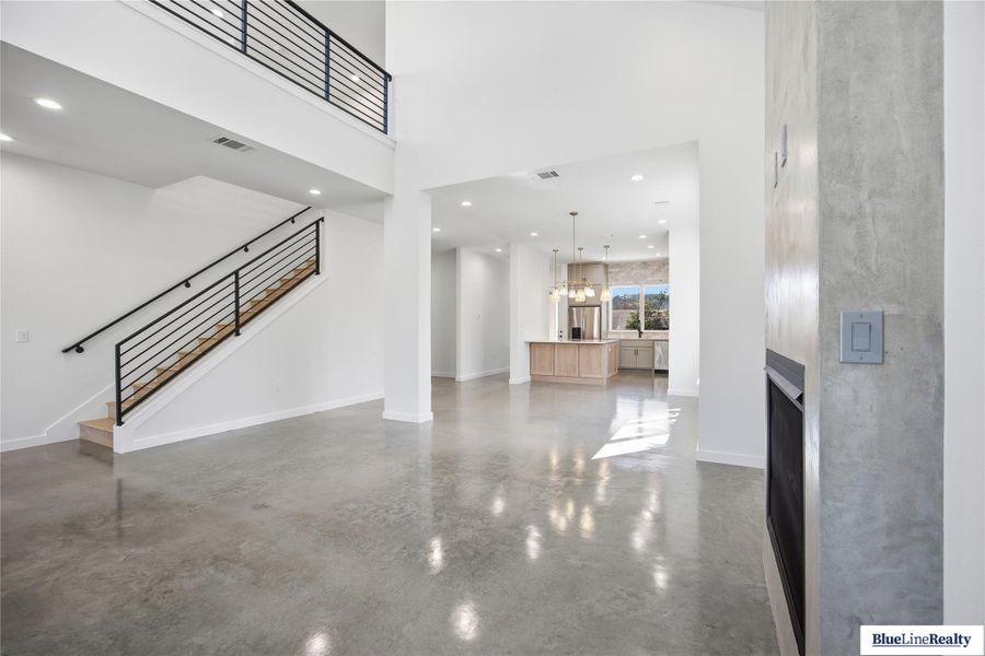 Unfurnished living room featuring finished concrete floors, a high ceiling, a chandelier, and a fireplace