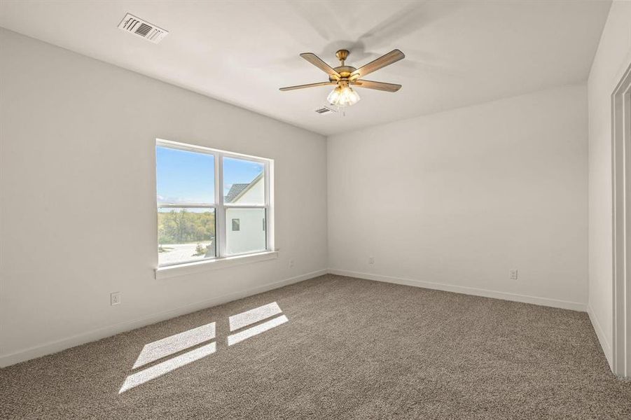 Carpeted empty room featuring ceiling fan and baseboards