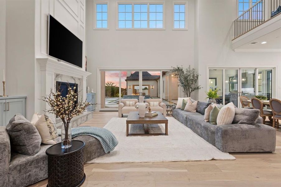 Living area featuring a towering ceiling, a premium fireplace, wood finished floors, and plenty of natural light Living area featuring a towering ceiling, a premium fireplace, wood finished floors, and plenty of natural light