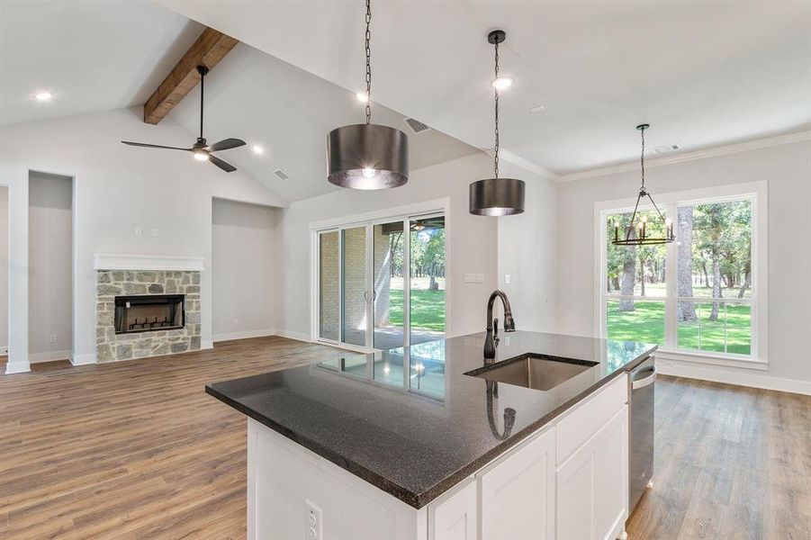 Kitchen with sink, a fireplace, a kitchen island with sink, and light wood-type flooring