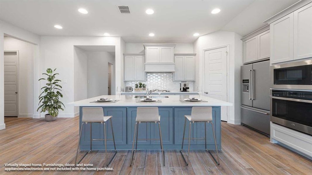 Kitchen with a center island with sink, light wood-type flooring, appliances with stainless steel finishes, and white cabinetry