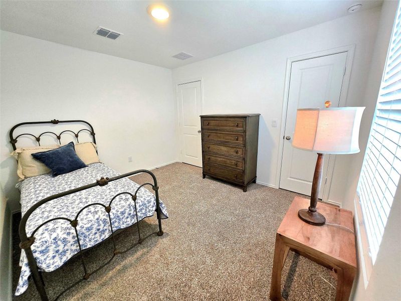Carpeted room with white walls, featuring a window with horizontal blinds, a white interior door, and a ceiling-mounted light fixture