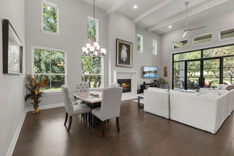 A spacious living area with vaulted ceilings, a cozy fireplace, and rich hardwood flooring flows to a delightful dining space.