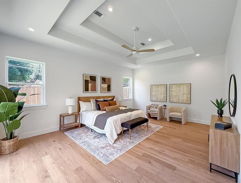 Bedroom with a tray ceiling, light wood-type flooring, ceiling fan, and recessed lighting Bedroom with a tray ceiling, light wood-type flooring, ceiling fan, and recessed lighting