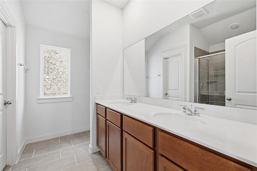 Full bath with double vanity, a shower stall, and light tile patterned flooring Full bath with double vanity, a shower stall, and light tile patterned flooring