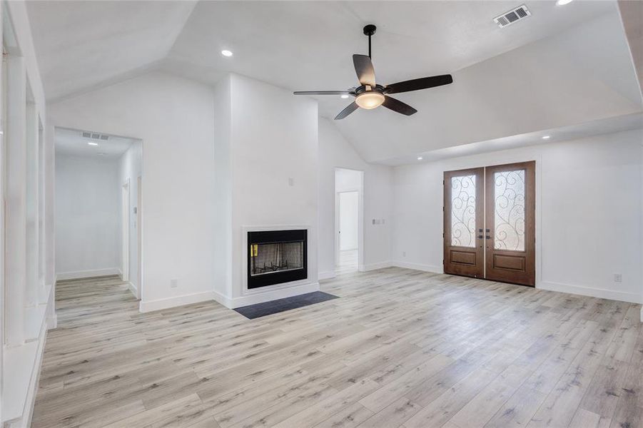 Unfurnished living room with french doors, light hardwood / wood-style floors, high vaulted ceiling, and ceiling fan