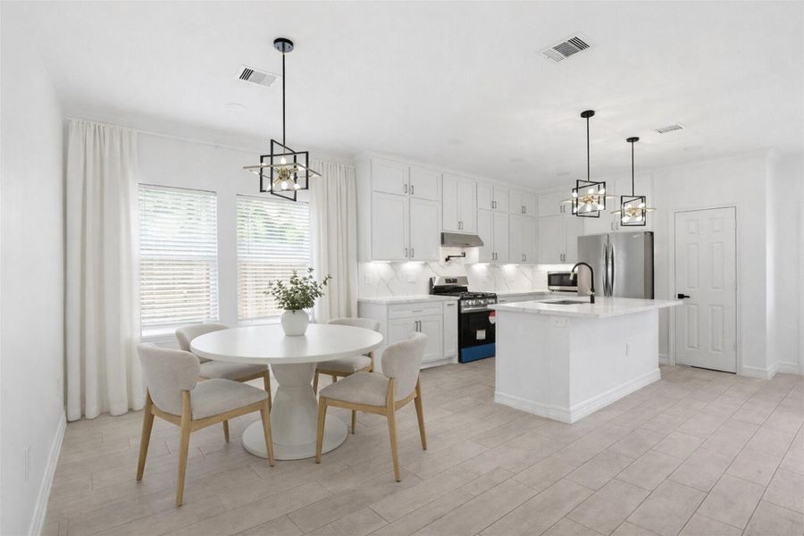 Bright dining area with round table, stylish pendant chandelier, and open views into the kitchen.