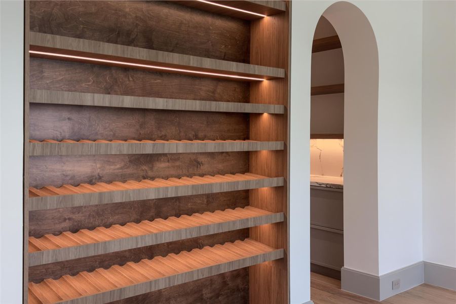This isn't a wine rack tucked into a corner. It's a floor-to-ceiling, custom-built display with individual bottle storage, rich wood backing, and integrated lighting. One of those just-finished details that makes the home feel entirely bespoke.