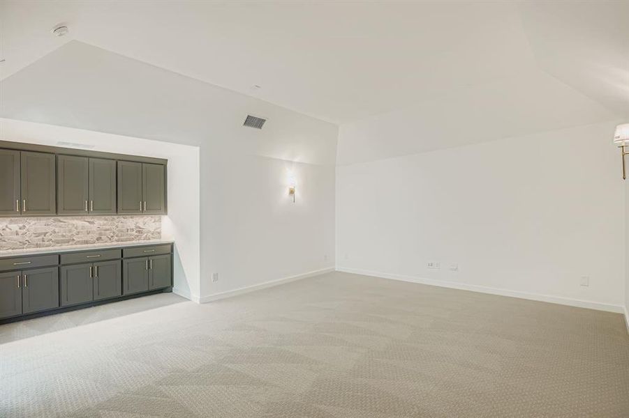Unfurnished living room featuring light carpet and vaulted ceiling Unfurnished living room featuring light carpet and vaulted ceiling