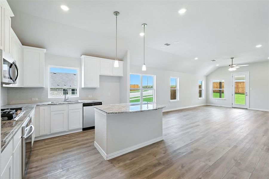 Kitchen with appliances with stainless steel finishes, vaulted ceiling, plenty of natural light, white cabinetry, and recessed lighting